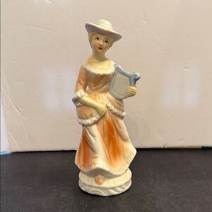 vintage ceramic figurine of a Victorian woman playing the harp